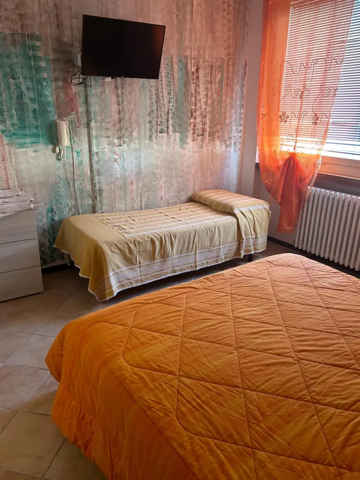 Camera tripla con il copriletto arancio e la parete decorata