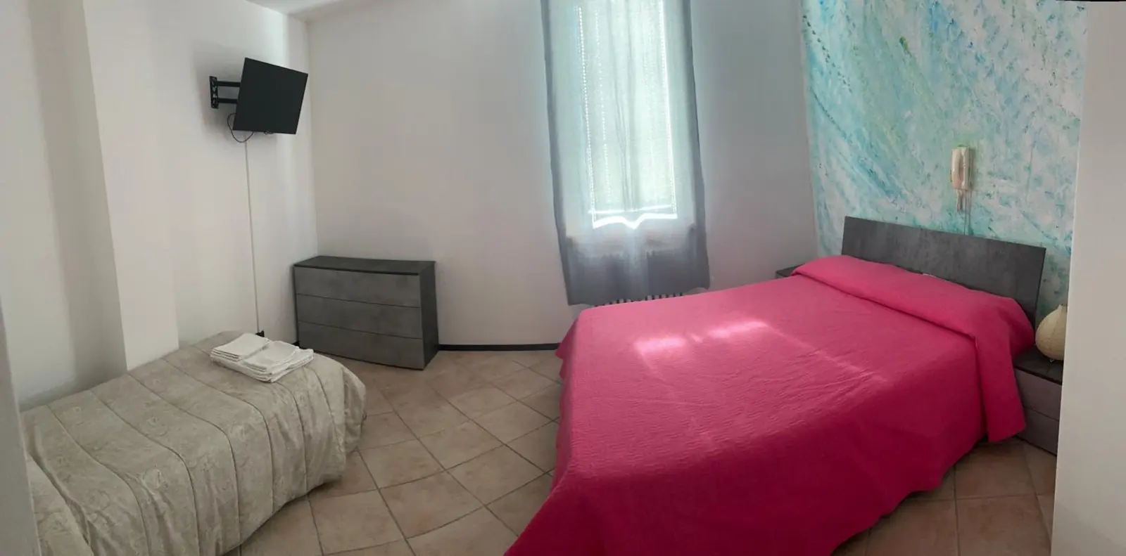 Camera ampia con letto matrimoniale e letto singolo, luce dalla finestra