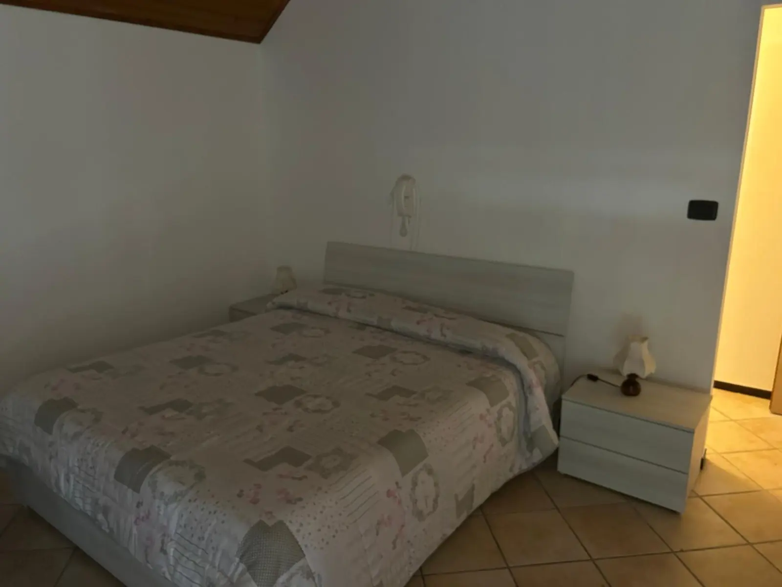 Camera mansardata con il soffitto in legno e il letto matrimoniale