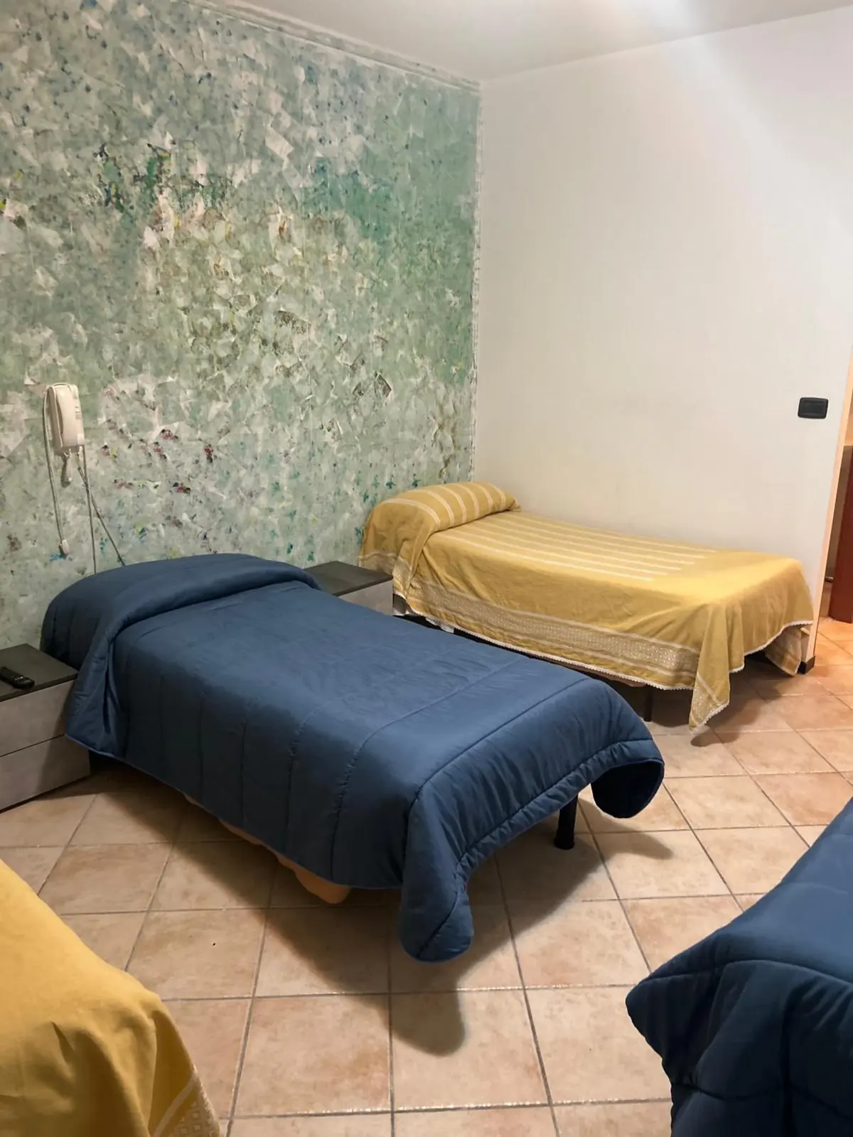 Camera con letti singoli blu e gialli e la parete decorata