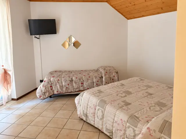 Camera mansardata con due letti e il soffitto in legno