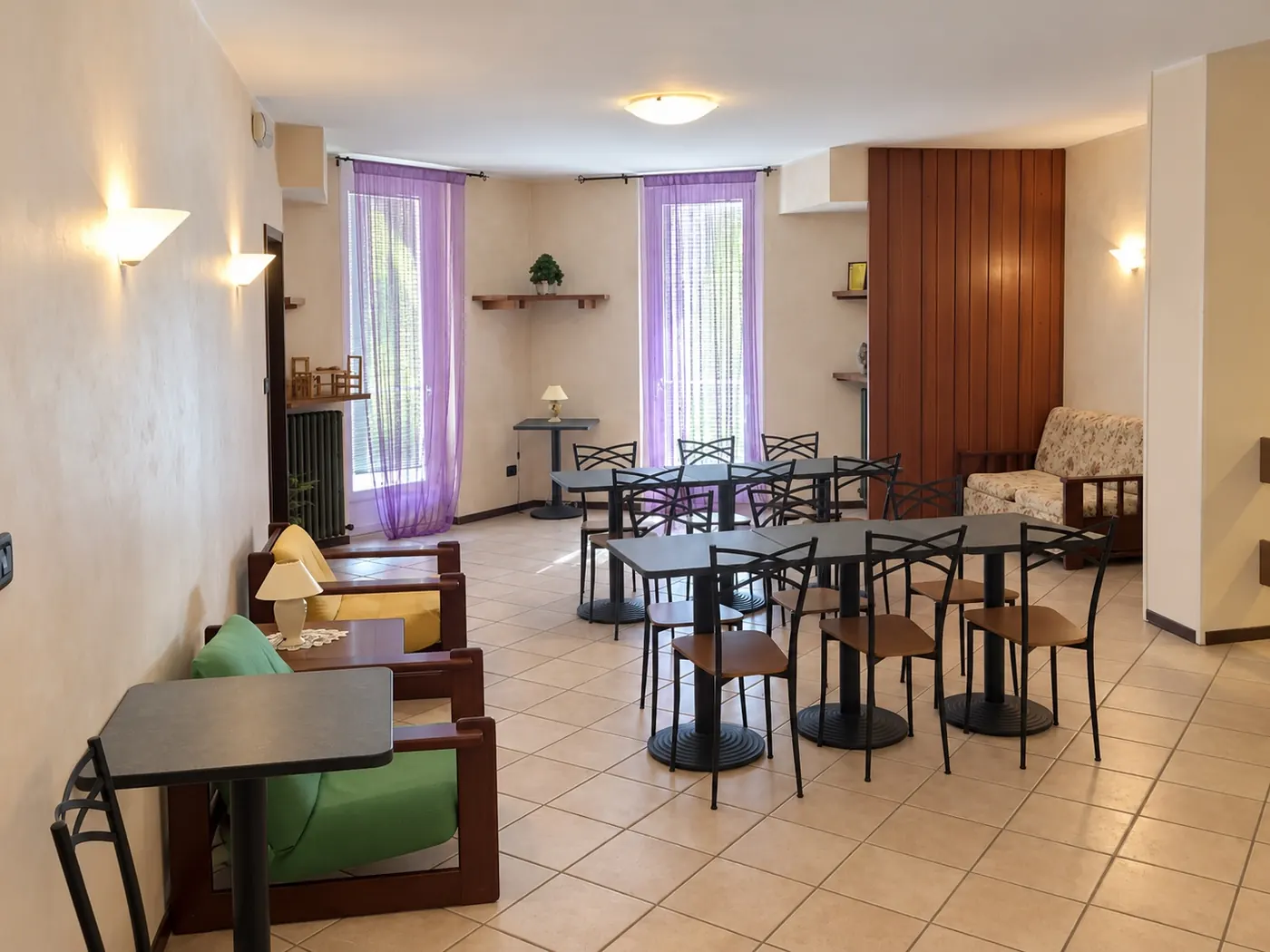 La sala della colazione, coi tavolini e le luci a muro