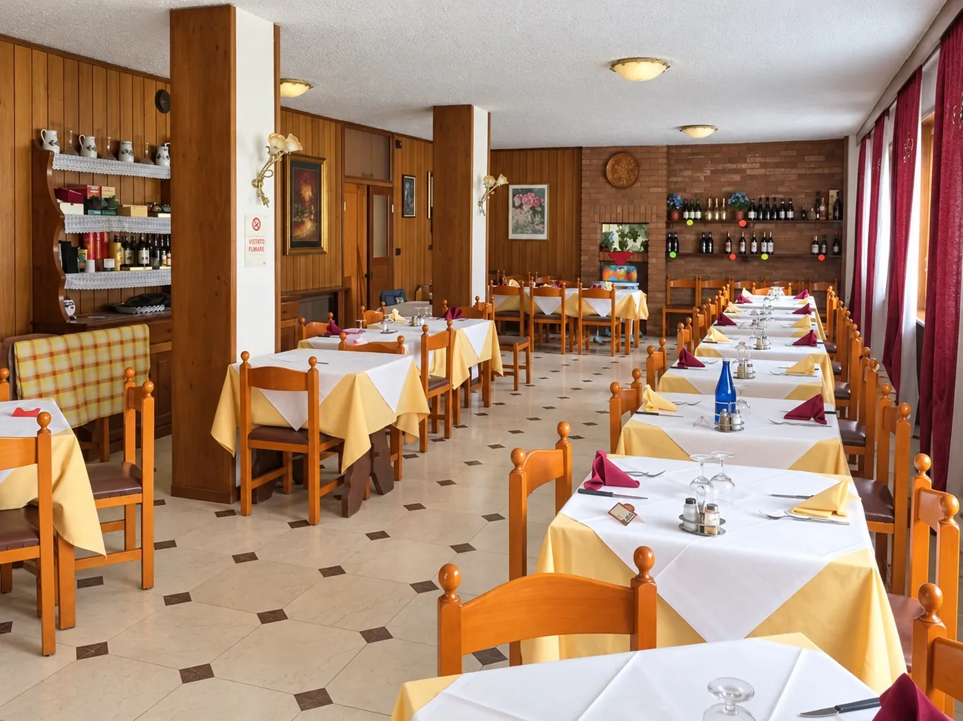 La sala del ristorante coi tavoli apparecchiati e le pareti in legno