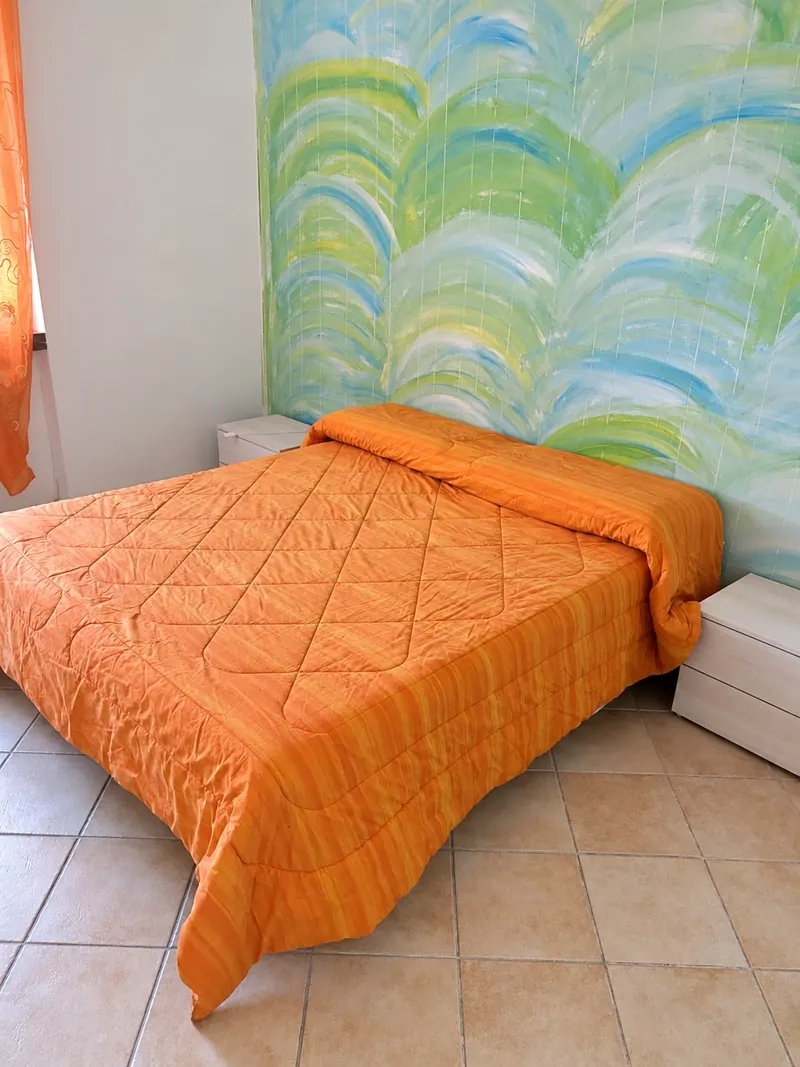 La camera matrimoniale arancio con la parete dipinta