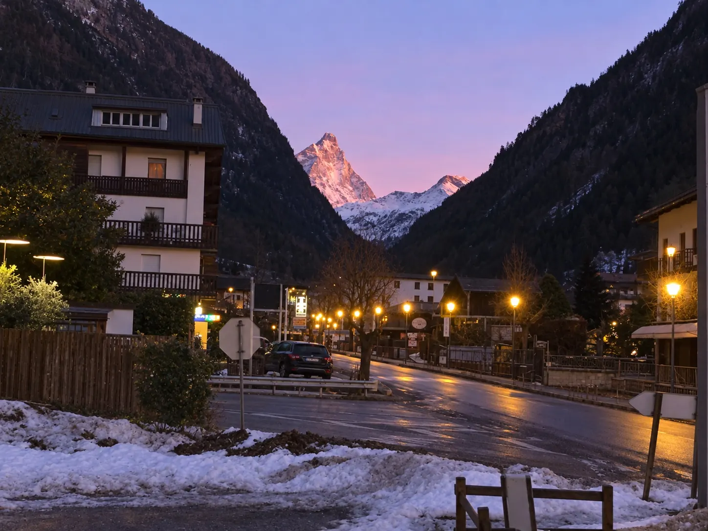 Il Cervino rosa al tramonto sopra la strada del paese, con la neve