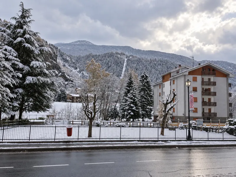 Il paese sotto la neve, con una pista da sci sulla montagna