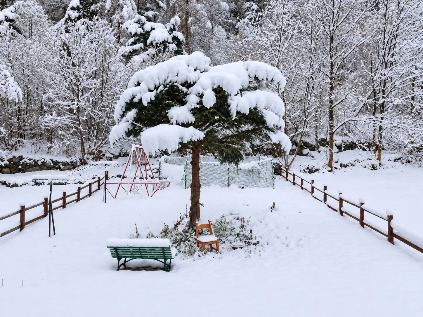 Il giardino dell'albergo sotto la neve, con la panchina e l'altalena